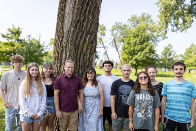 Extended Family Under a Shade Tree Extended family of eleven standing together beneath a large shade tree in a sunlit park