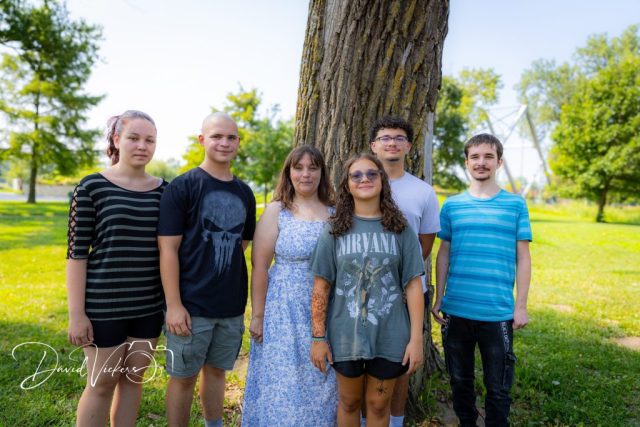 Siblings and Cousins Together Six siblings and cousins standing shoulder to shoulder in front of a broad tree trunk