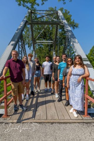 Family Walking the Iron Bridge Family group walking together across a historic iron truss footbridge on a clear summer day