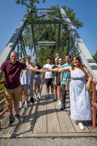 Family Group on the Truss Bridge Extended family standing along the railing of a steel truss footbridge with hands joined in the center