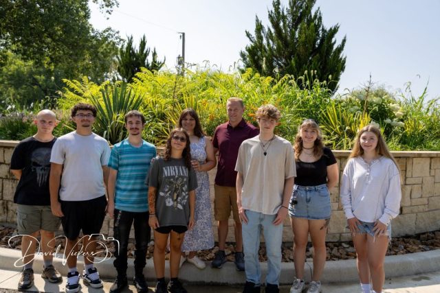 Family by the Garden Wall Extended family of ten standing together in front of a stone garden wall and ornamental grasses