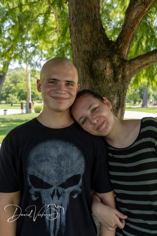 Couple in a Quiet Moment Young couple standing close, her head resting on his shoulder, beneath a shade tree