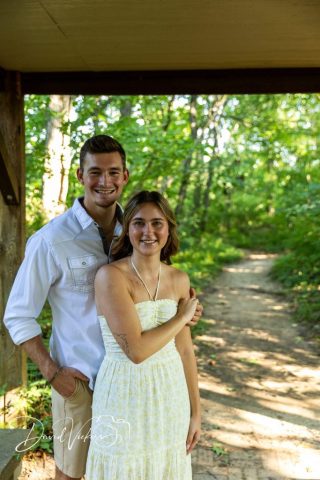 1g2a4984 Engaged couple standing together under a wooden pavilion at the head of a wooded trail