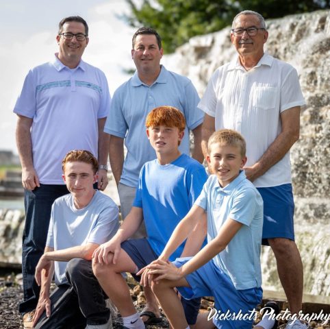 Three Generations by the Waterfall Three generations of men and boys in coordinated blue standing beside a stone waterfall