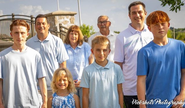 Extended Family Portrait Outdoors Extended family of nine in coordinated blue standing together on a sunny summer afternoon