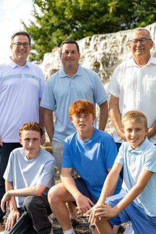 Three Generations of Men Three generations of men and boys standing together beside a cascading stone waterfall