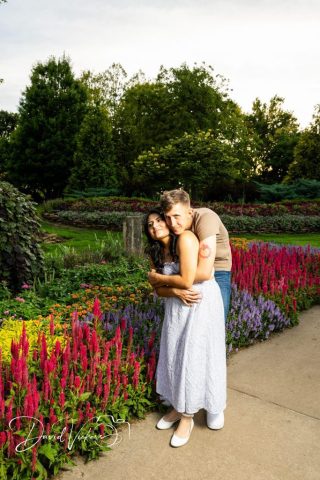 engagement session in the flower garden Engaged couple embracing on a path lined with pink and purple flowers