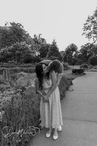 black and white engagement photo Black and white photo of an engaged couple kissing on a garden path