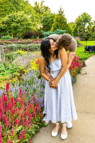 kiss among the garden flowers Engaged couple kissing on a garden path surrounded by blooming flowers