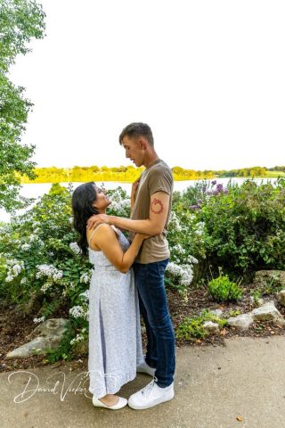 lakeside engagement portrait Engaged couple embracing in front of a lake at golden hour