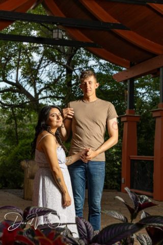 engagement portrait under a garden pergola Engaged couple standing together under a garden pergola