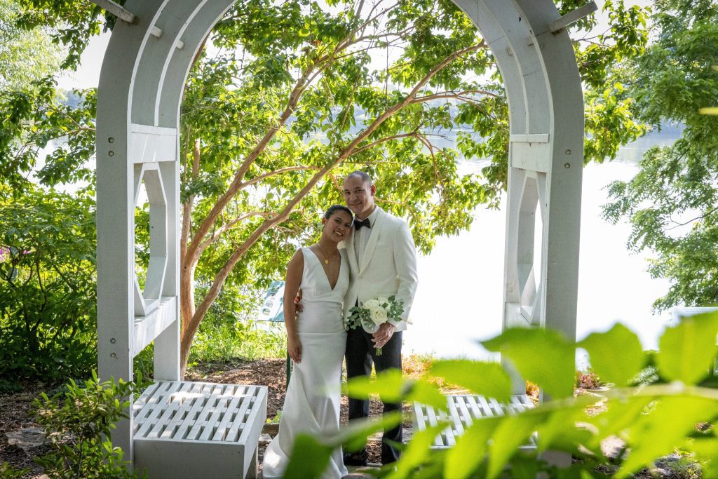 Wedding Photography Bride and groom embracing under a white garden arbor by the lake, Kansas City wedding photography