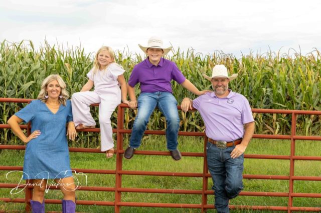 Ferguson family members on a red farm gate by a cornfield Ferguson family members on a red farm gate by a cornfield