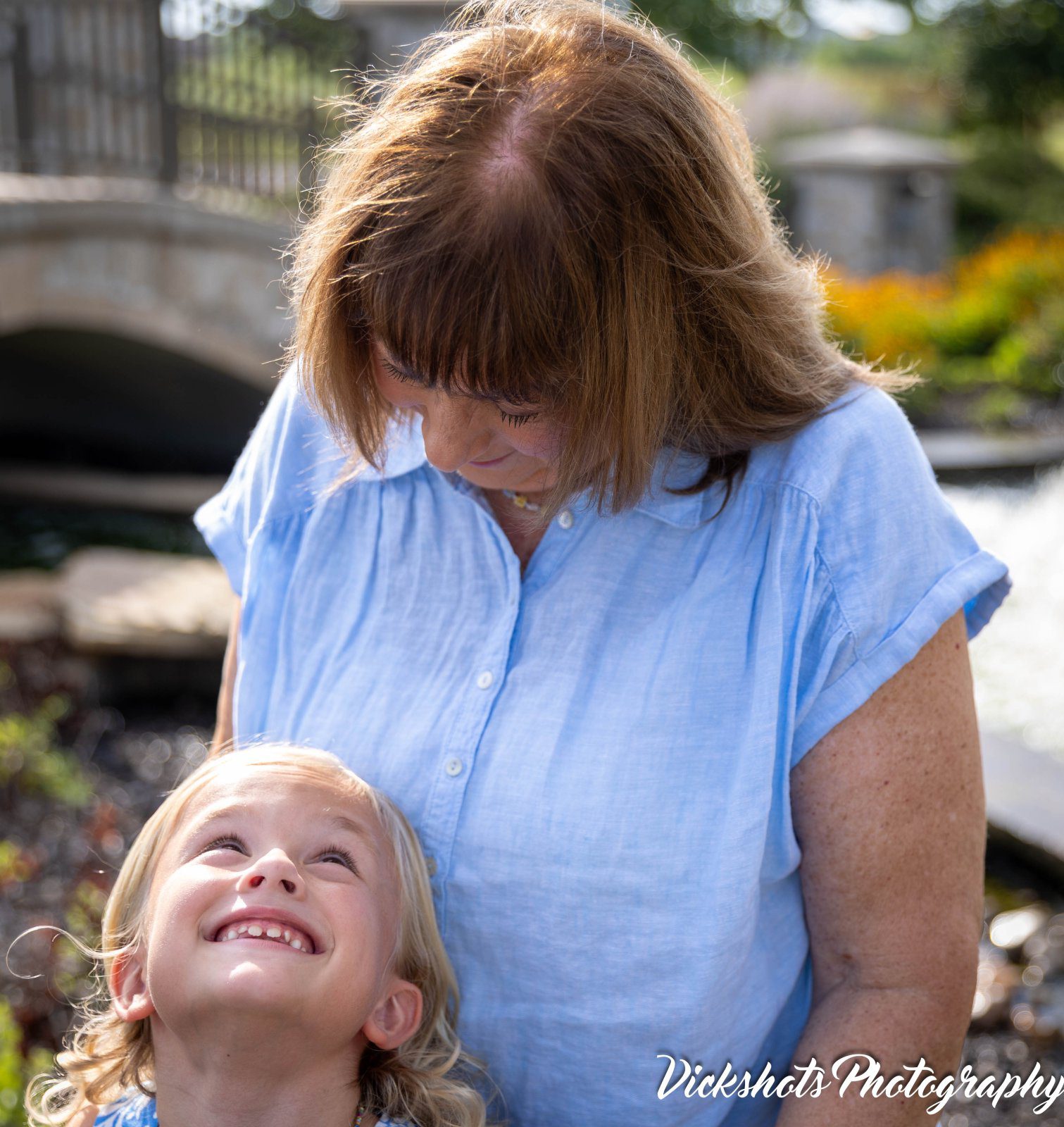 Little girl looking up and smiling at her grandmother in soft natural light